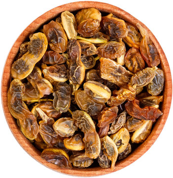 Dried sophora japonica beans in a small wooden bow isolated on w