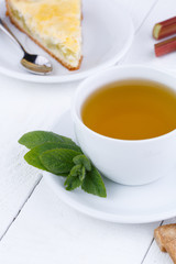 Mint tea with slice of rhubarb pie on wooden table.
