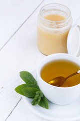 Mint tea with honey on wooden table.