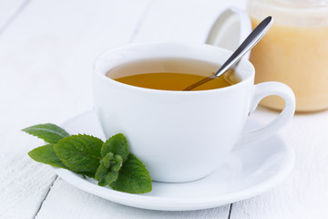 Mint tea with honey on wooden table.