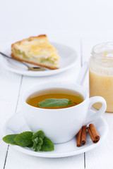 Mint tea with cinnamon on wooden table.