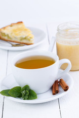 Mint tea with cinnamon on wooden table.