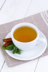Mint tea with cinnamon on wooden table.