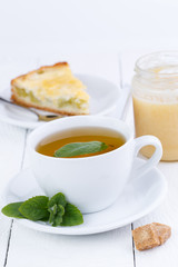 Mint tea with slice of rhubarb pie on wooden table.