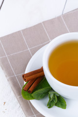 Mint tea with cinnamon on wooden table.