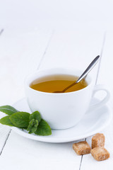 Mint tea with brown sugar on wooden table.
