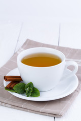 Mint tea with cinnamon on wooden table.