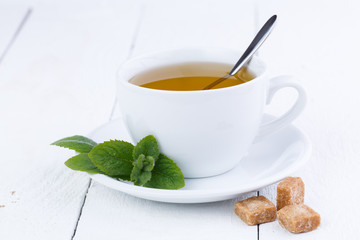 Mint tea with brown sugar on wooden table.