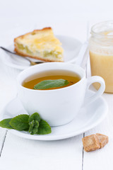 Mint tea with slice of rhubarb pie on wooden table.