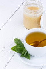 Mint tea with honey on wooden table.