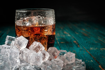 Fototapeta Glass of cola with ice on a wooden table. obraz