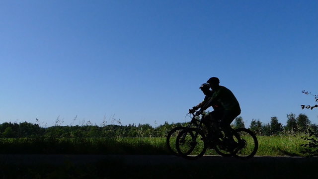 Mountainbiker fahren als Silhouette vorbei, in Zeitlupe