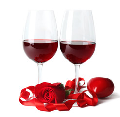 Composition with red wine in glasses, red rose, ribbon and decorative hearts isolated on white