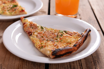 Tasty slices of pizza on plates with glass of juice on wooden table