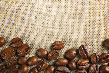 Frame of coffee beans on color sackcloth background