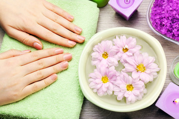 Female hands with bowl of aroma spa water on wooden table, closeup