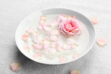 Fototapeta na wymiar Bowl of aroma spa water with rose petals on towel, closeup