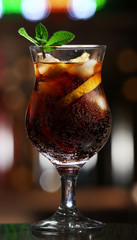 Glass of cocktail in bar on bright blurred background