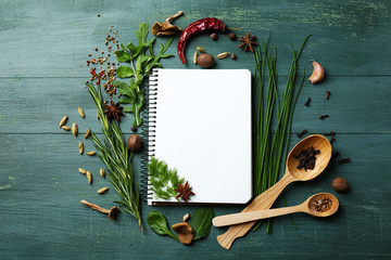 Open receptenboek met verse kruiden en specerijen op houten achtergrond