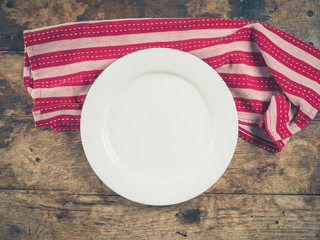 White plate and tea towel on wooden table