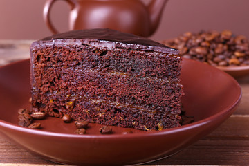 Delicious chocolate cake with coffee beans on plate on table close up
