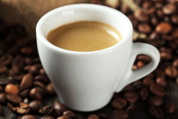Cup of coffee with beans on table close up
