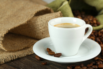 Cup of coffee with beans on table close up