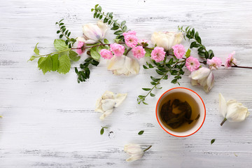 Cup of tea with beautiful flowers on wooden background