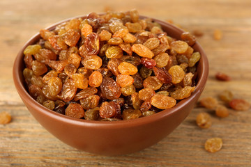 Raisins in bowl on wooden table, closeup