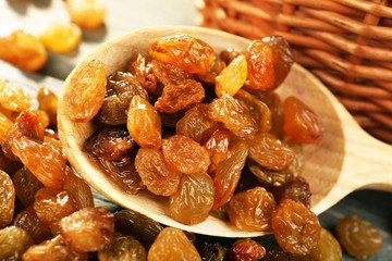 Raisins in spoon on wooden table, closeup