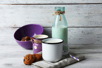Milk in mug with walnuts and cookies on wooden background