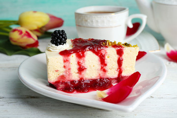 Tasty piece of cheesecake with berry sauce on plate on table close up