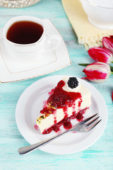 Tasty piece of cheesecake with berry sauce on plate on table close up
