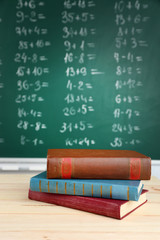 Stack of books on desk, on blackboard background