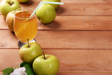Glass of apple juice and apples on wooden table
