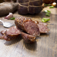Smoked dried gammon and slices of sausages with bread on wooden board