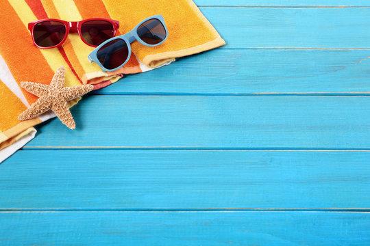 Beach background border scene with old blue wood deck decking sunglasses and sunbathing towel summer holiday vacation photo