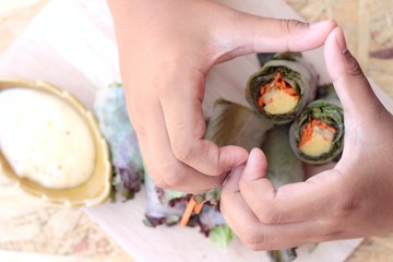 Vegetable salad wrapped into spring rolls with heart-shaped hand
