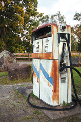 Rusted on pump put the front of an abandoned fuel station.