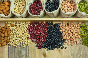 Different kinds of beans scattered on wooden background