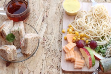 Pasta spaghetti with salad mix fruit and bread sandwich.