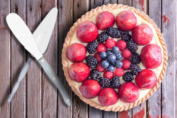 Fresh Berries Tart on Rustic Wooden Table with Serving Utensils