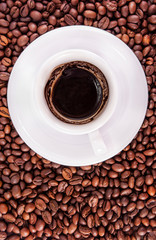 White cup with coffee grounds and saucer on beans background - t