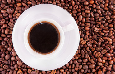 White cup of black coffee on a beans background