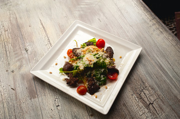 Caesar salad with meat, leafs and tomatoes on white plate