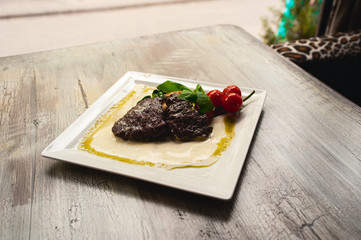 Grilled beef steak and mushrooms with tomatoes on white plate