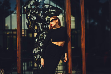 fashion girl posing in sunglasses near the glass windows