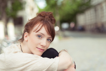 schöne junge frau mit blauen augen sitzt entspannt draußen in der stadt
