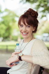 lächelnde frau mit einer flasche wasser im park