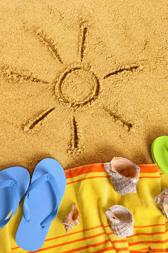 Summer sun drawing drawn on a sand beach with towel seashell and flip flop sandals happy relaxed vacation holiday photo vertical